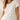 A woman wearing a short-sleeve crew-neck t-shirt in off-white, paired with light-wash blue jeans, shown from the waist up against a neutral beige background.