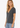 A woman wearing a dark charcoal gray short-sleeve V-neck t-shirt and light blue jeans, photographed against a clean white studio background.